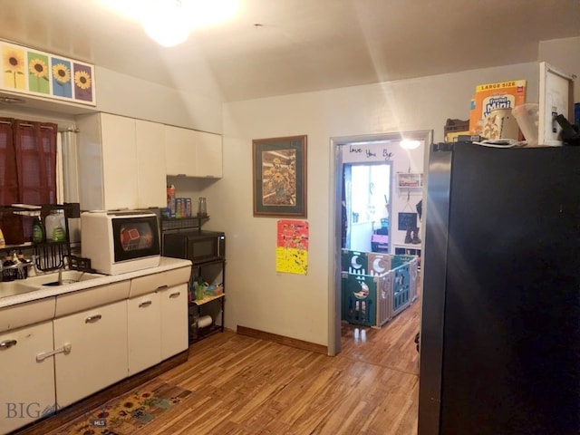 kitchen with white cabinets, light wood-type flooring, and refrigerator