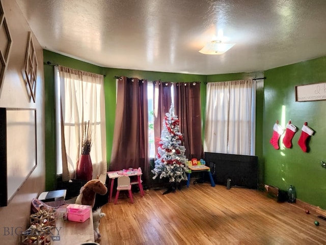 game room with hardwood / wood-style floors, a textured ceiling, and a wealth of natural light