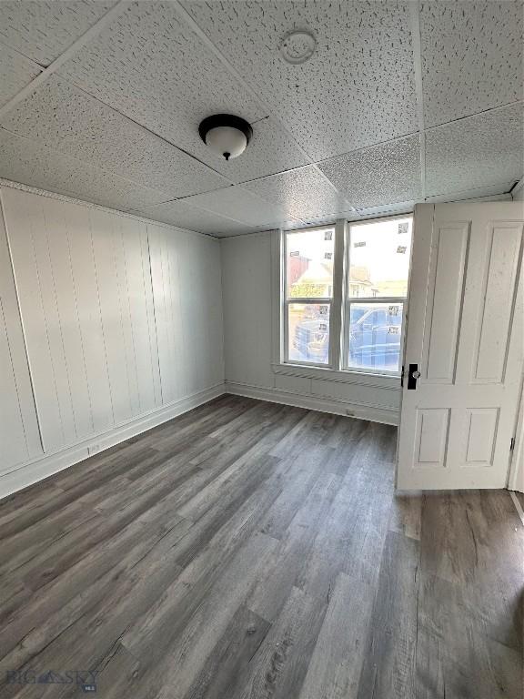 spare room with dark hardwood / wood-style floors and a drop ceiling