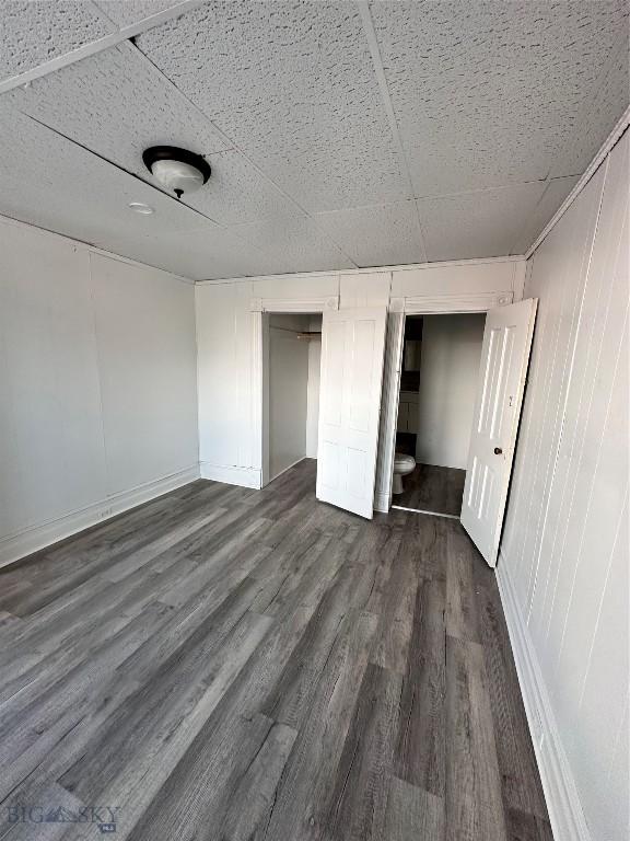 unfurnished bedroom featuring dark hardwood / wood-style floors and a drop ceiling