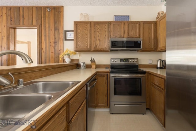 kitchen with a textured ceiling, sink, and stainless steel appliances