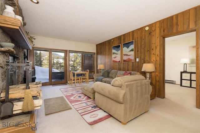 living room with a textured ceiling, wood walls, baseboard heating, and light carpet