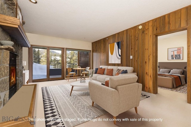 living room featuring a textured ceiling, a stone fireplace, and wooden walls