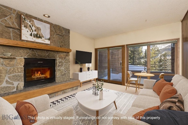 living room with a textured ceiling and a stone fireplace