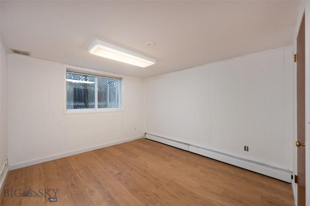 spare room featuring baseboard heating and light hardwood / wood-style flooring