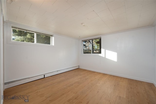 empty room with baseboard heating, a wealth of natural light, and light hardwood / wood-style flooring