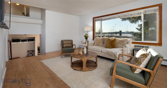 living room featuring wood-type flooring, a textured ceiling, and a wall unit AC