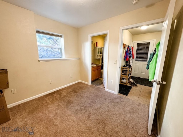 unfurnished bedroom with a spacious closet, ensuite bath, light colored carpet, and a closet