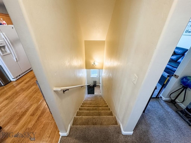 staircase with hardwood / wood-style floors and a towering ceiling