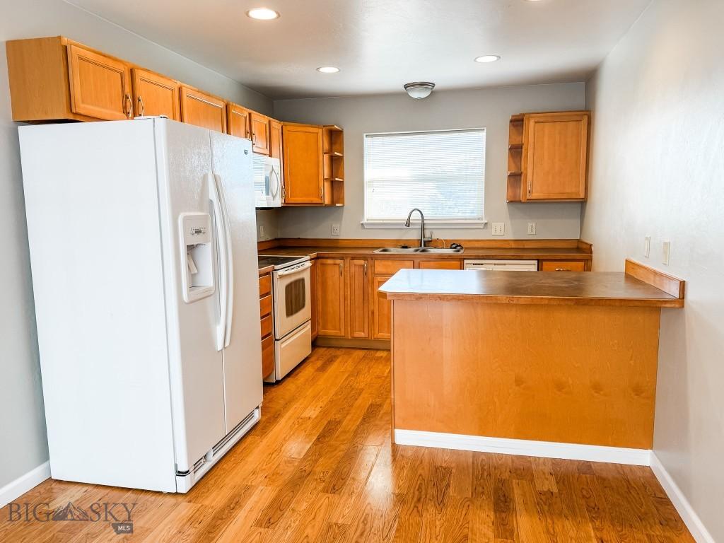 kitchen featuring white appliances, kitchen peninsula, sink, and light hardwood / wood-style flooring