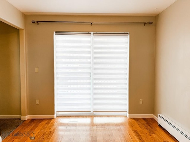 spare room featuring hardwood / wood-style flooring, a baseboard radiator, and a wealth of natural light