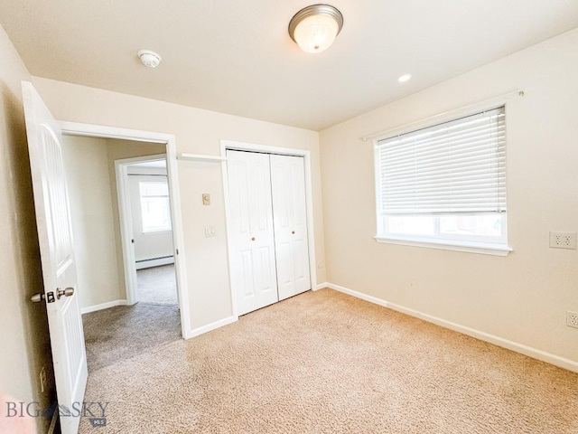 unfurnished bedroom featuring a baseboard radiator, carpet floors, and a closet