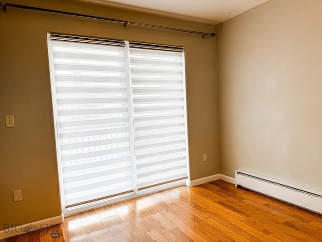 unfurnished room featuring baseboard heating and light hardwood / wood-style flooring