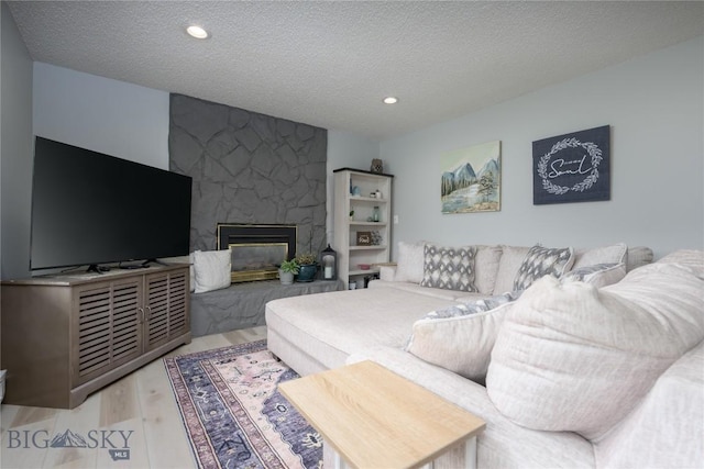 living room featuring a fireplace, a textured ceiling, and light hardwood / wood-style flooring