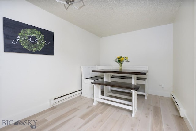 dining area with light hardwood / wood-style floors, a textured ceiling, and a baseboard radiator