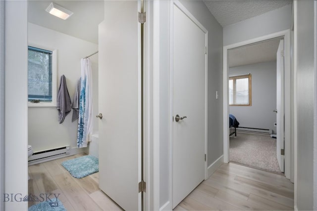 bathroom featuring shower / tub combo with curtain, wood-type flooring, a textured ceiling, and a baseboard radiator