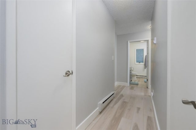 hallway with a baseboard radiator, a textured ceiling, and light wood-type flooring