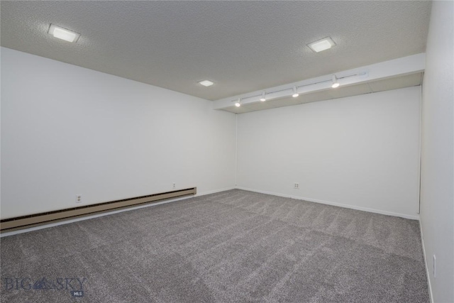 carpeted empty room with a textured ceiling, rail lighting, and a baseboard heating unit