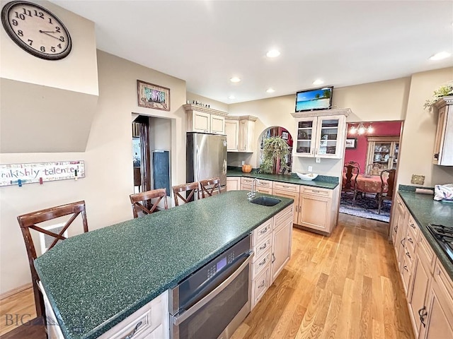 kitchen featuring a center island, sink, light wood-type flooring, appliances with stainless steel finishes, and cream cabinetry