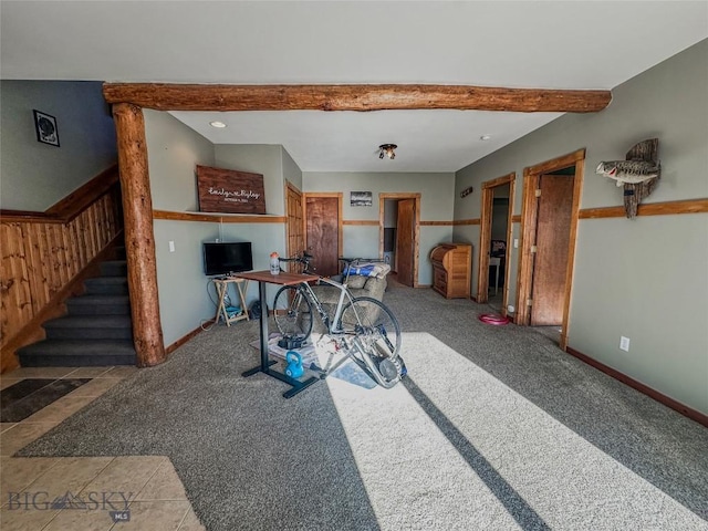 carpeted dining space with wood walls and beam ceiling