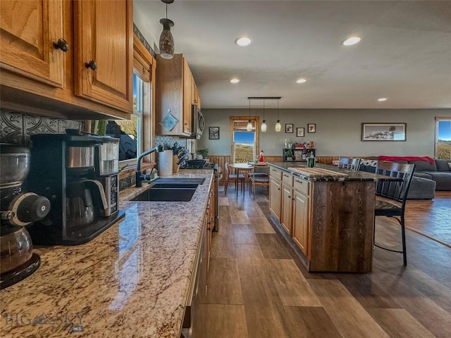 kitchen featuring appliances with stainless steel finishes, a center island, dark hardwood / wood-style floors, and light stone counters