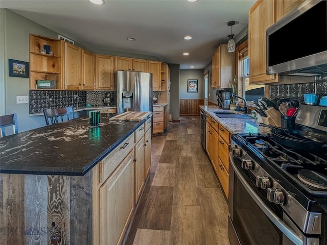 kitchen featuring sink, hardwood / wood-style flooring, decorative backsplash, a kitchen island, and stainless steel appliances