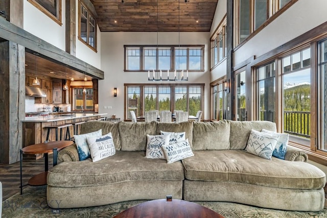 living room with a high ceiling, an inviting chandelier, and wood ceiling