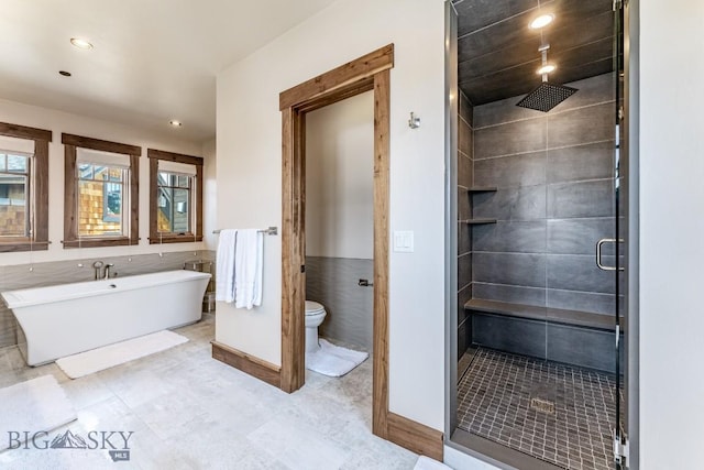 bathroom with plus walk in shower, tile patterned flooring, toilet, and tile walls