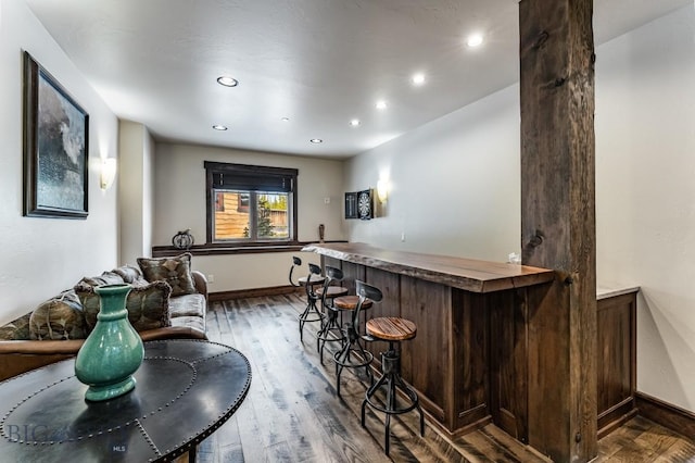 bar featuring dark brown cabinets and dark hardwood / wood-style flooring