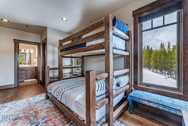 bedroom featuring connected bathroom, hardwood / wood-style flooring, and multiple windows