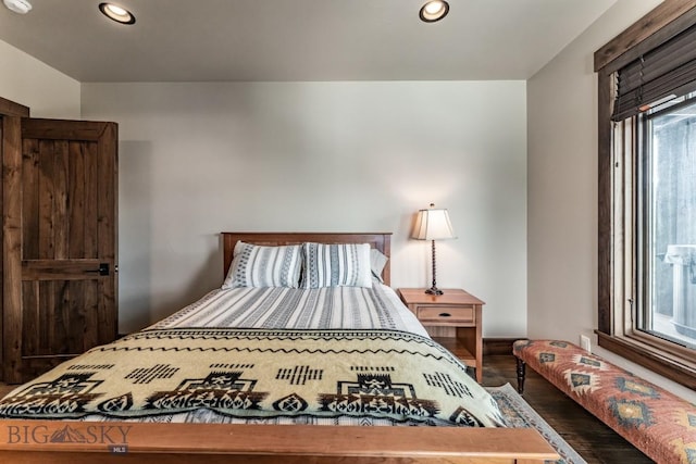 bedroom with multiple windows and dark wood-type flooring