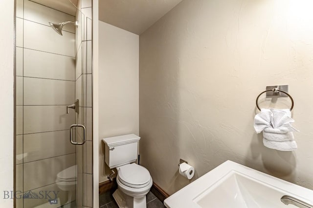 bathroom with a shower with door, tile patterned flooring, and toilet