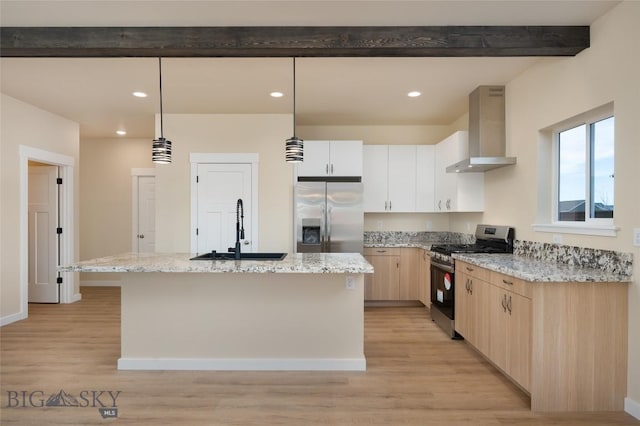 kitchen featuring wall chimney exhaust hood, appliances with stainless steel finishes, light wood-style floors, light brown cabinets, and a sink