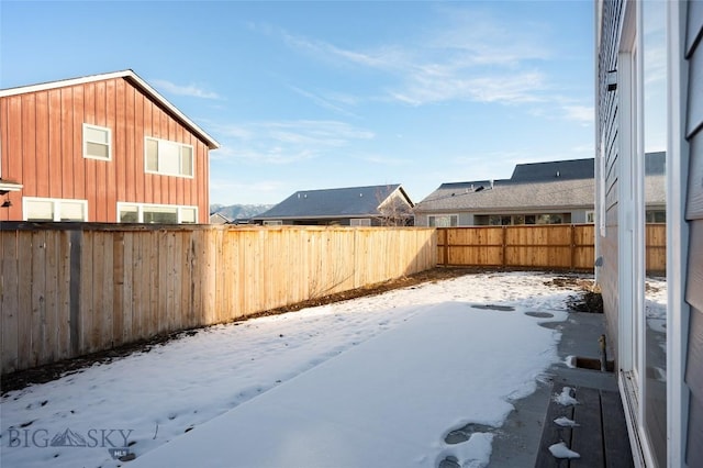 snowy yard with a fenced backyard