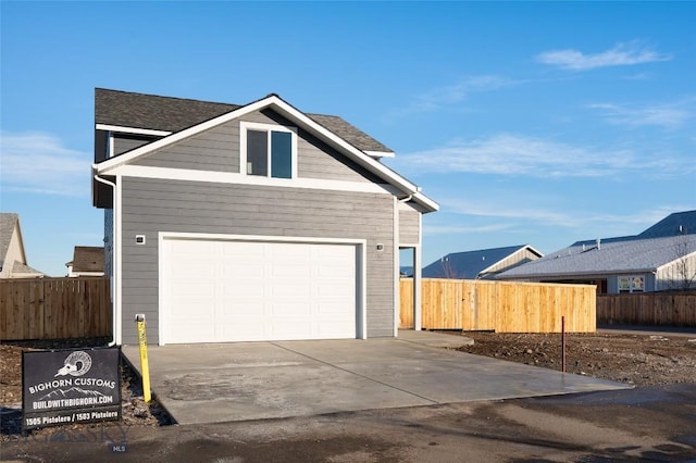 view of front of house featuring a garage, concrete driveway, and fence