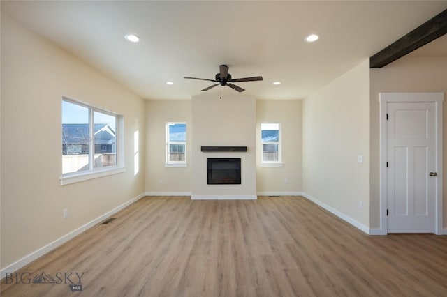 unfurnished living room with recessed lighting, visible vents, light wood-style floors, baseboards, and a glass covered fireplace