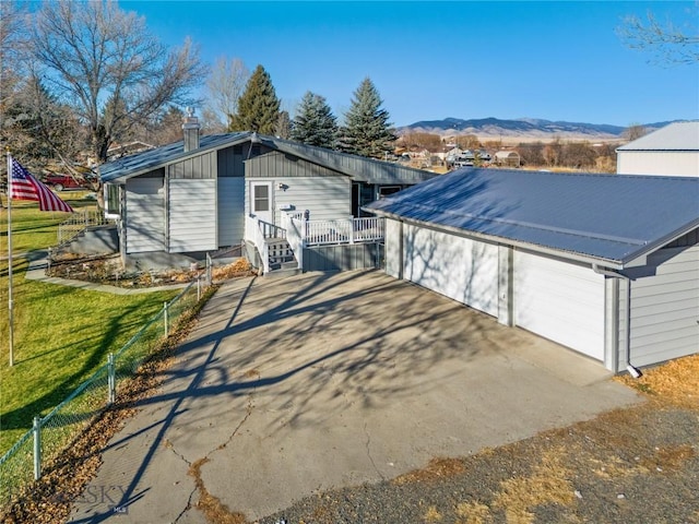 exterior space with a garage, a lawn, metal roof, fence, and a mountain view