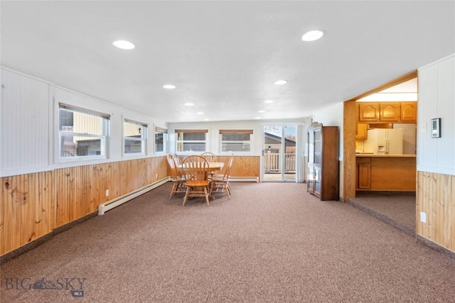 unfurnished dining area with a baseboard radiator, carpet flooring, wooden walls, and recessed lighting