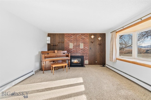 sitting room with baseboard heating, carpet, a fireplace, and wooden walls