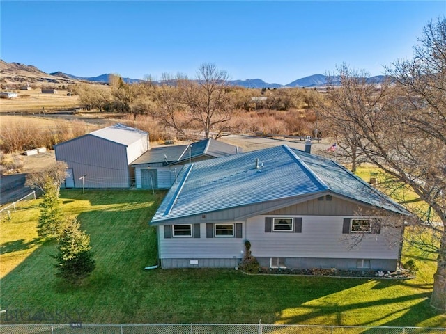 rear view of house with fence, a mountain view, and a yard