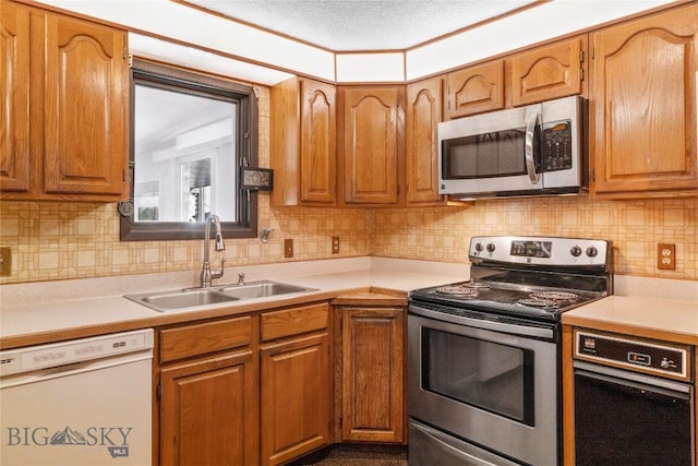 kitchen featuring a sink, brown cabinetry, stainless steel appliances, and light countertops