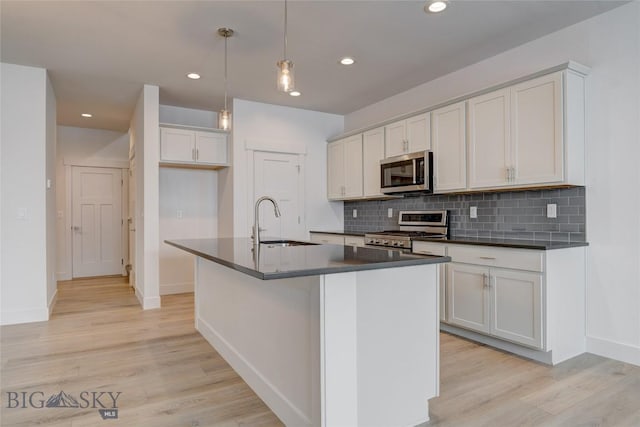 kitchen featuring sink, pendant lighting, stainless steel appliances, and a kitchen island with sink