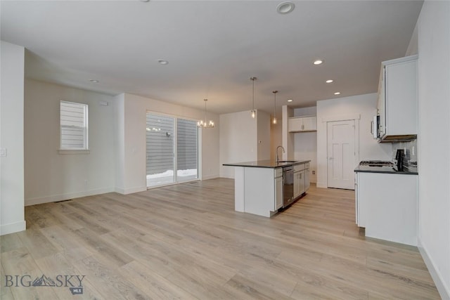 kitchen with pendant lighting, stainless steel dishwasher, sink, a kitchen island with sink, and white cabinets