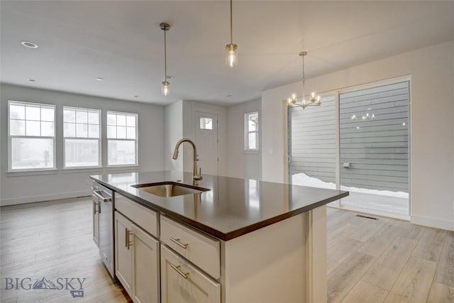 kitchen with an island with sink, a wealth of natural light, sink, and pendant lighting