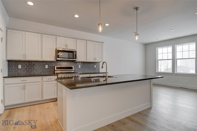 kitchen featuring decorative light fixtures, white cabinets, sink, and stainless steel appliances