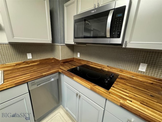 kitchen featuring white cabinets, wood counters, stainless steel appliances, and tasteful backsplash