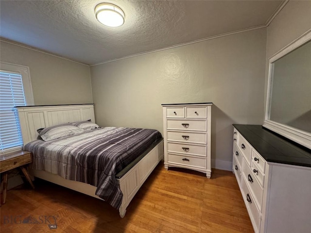 bedroom featuring crown molding, light wood-type flooring, and a textured ceiling