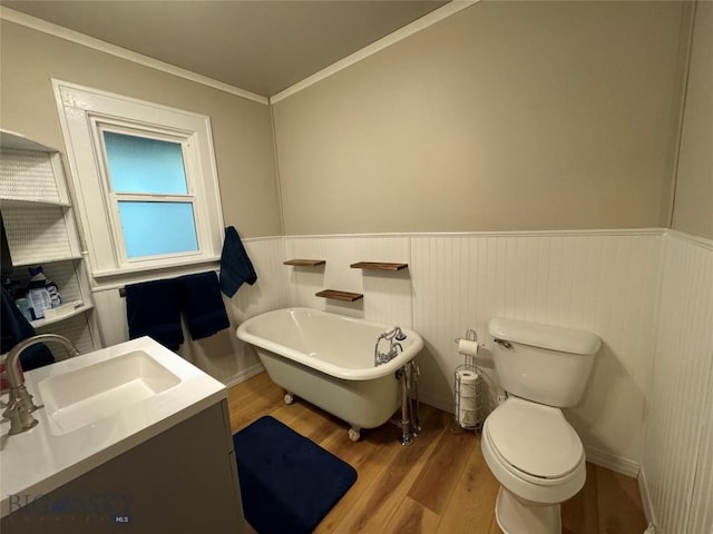 bathroom featuring a bath, crown molding, hardwood / wood-style floors, toilet, and vanity