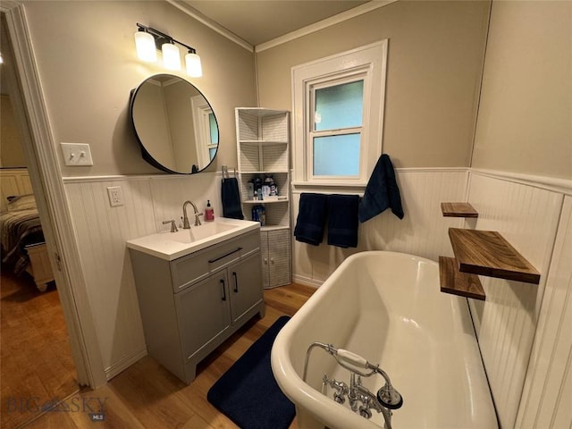 bathroom with hardwood / wood-style flooring, a washtub, crown molding, and vanity