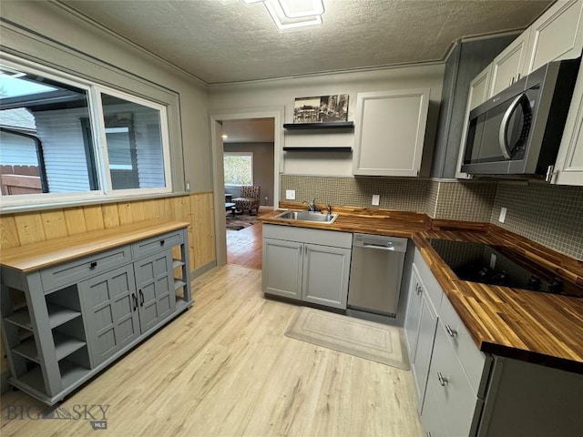 kitchen featuring wood counters, appliances with stainless steel finishes, gray cabinetry, a textured ceiling, and light hardwood / wood-style floors